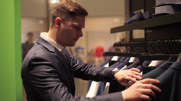 Man Choosing Business Jacket From The Raw In The Shop.