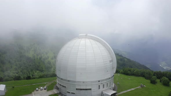 Aerial view of Astrophysical observatory, BTA tower. Drone goes up. Clouds. Nizhny Arkhyz, Russia