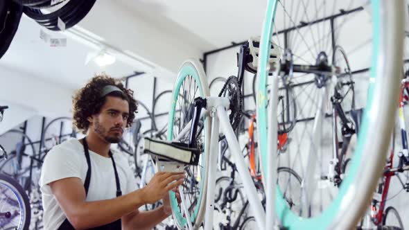 Mechanic repairing bicycle in workshop alt