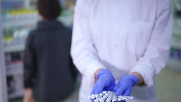 Front View Unrecognizable Druggist Stretching White Pills in Blisters to Camera Standing in alt