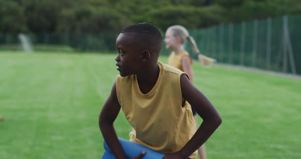 African american schoolboy rolling mat after yoga class outside alt