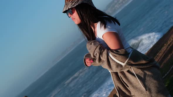 Rotating portrait of a beautiful young Latin woman in a sunset, pichilemu, chile. alt