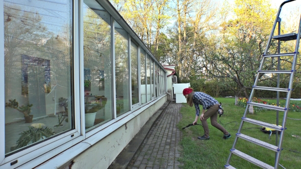 Girl Cleaning Hothouse Windows With a Water Jet Pressure.