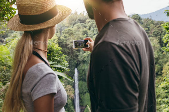 Young couple taking a picture of water fall - Stock Photo - Images