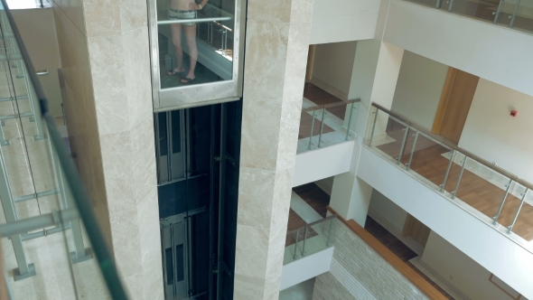 A Female Is Standing In Glass Moving Lift