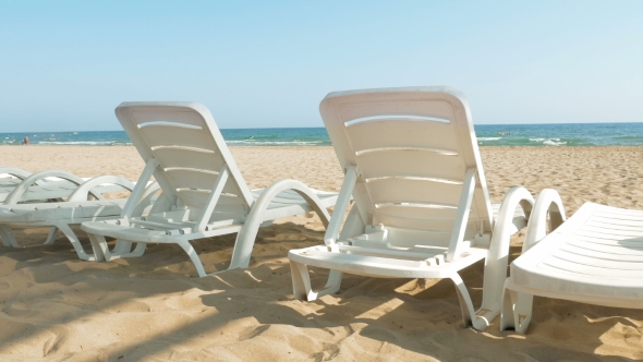 White Beach Chairs Or Beds Near Sea Or Ocean Shore