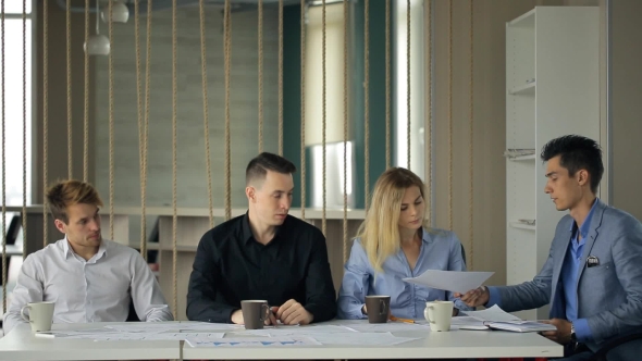 Man In Suit Jacket Give Through Chain, Documents Woman And Other People Sitting At Same Table.