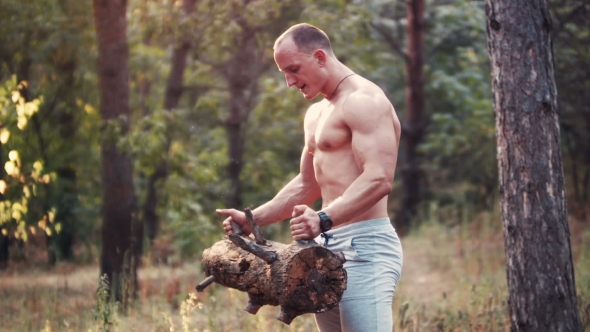 Muscular Topless Sportsman Doing Biceps Curls in Forest alt
