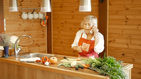 Elderly Woman Slices Carrots and Answers the Call alt
