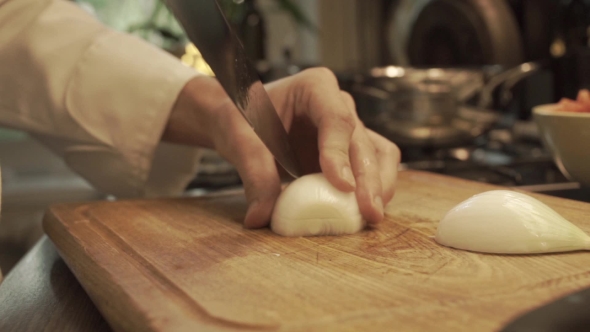 Male Hands Chopping Onion On a Wooden Cooking Board