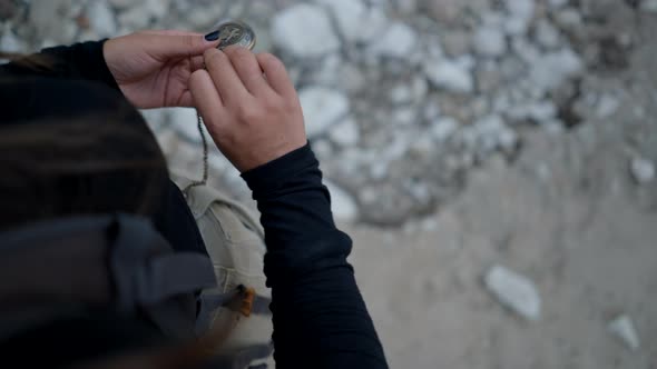 Girl Takes Compass Out of Pocket and Opens It Overtheshoulder View alt