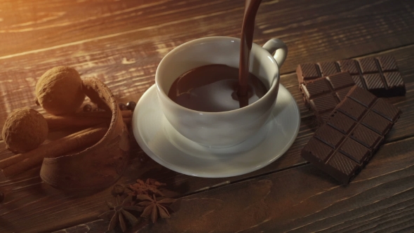 Cup Of Hot Chocolate, Cinnamon Sticks, Nuts And Chocolate Bar On Wooden Table