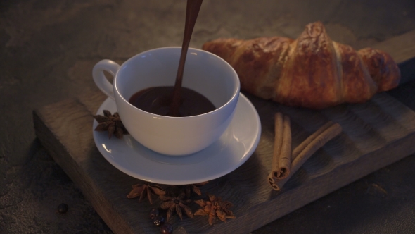 Pouring Hot Chocolate With Croissants And Cinnamon Sticks On Grunge Table