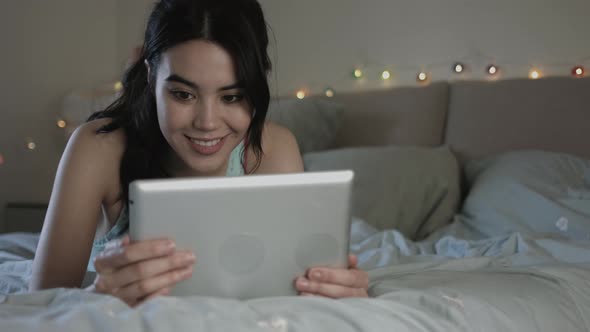 Young woman in Bedroom looking using digital tablet