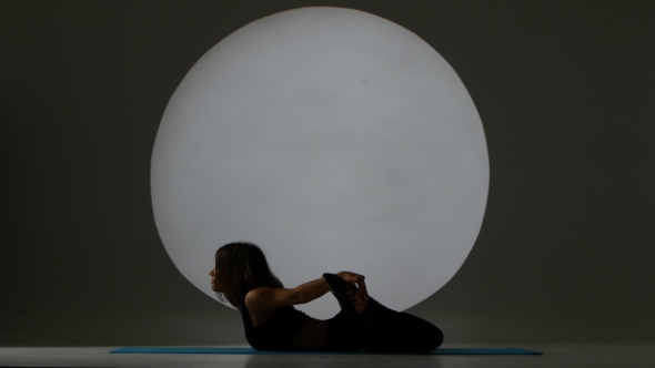 Girl In Pose On The Stomach Does Stretch. Back Light. Silhouette alt