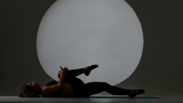 Gymnast Does The Splits Lying On Back. Back Light. Silhouette alt