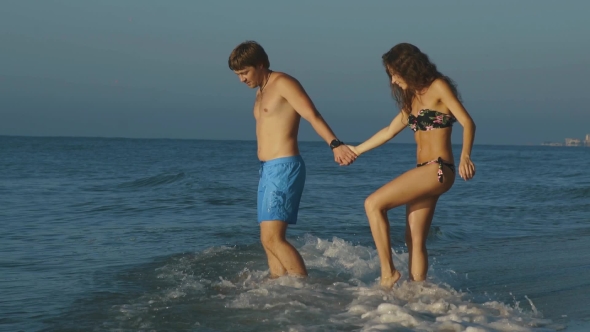 Happy Young Couple On Sunny Beach Go To Sea. Honeymoon Concept