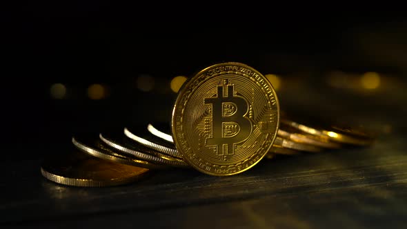 Handful of Bitcoins Stacked on Top of Each Other on a Table One Stands on an Edge of a Black Gold alt