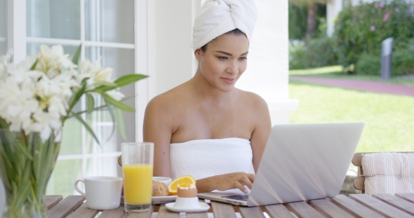 Young Woman Using a Laptop While Having Breakfast alt