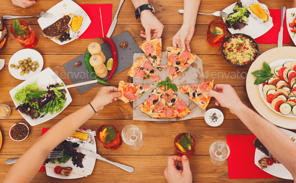 People eat pizza at festive table dinner party