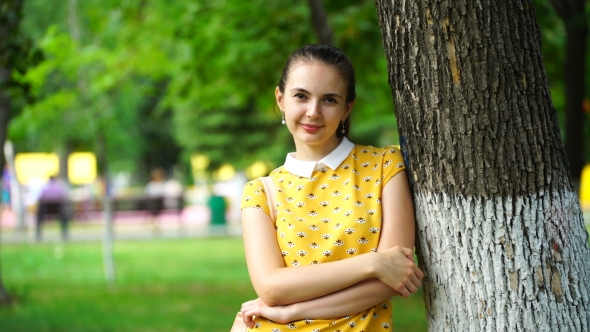 Footage Woman Walking In The Park And Stopped At The Tree, Looking At The Camera. 