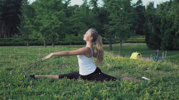 Blonde Girl Sits On a Hill And Doing The Exercises Right And Left Turns. alt