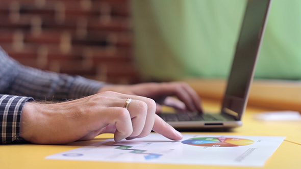 A Man Working On a Laptop And Analyzes The Graph alt