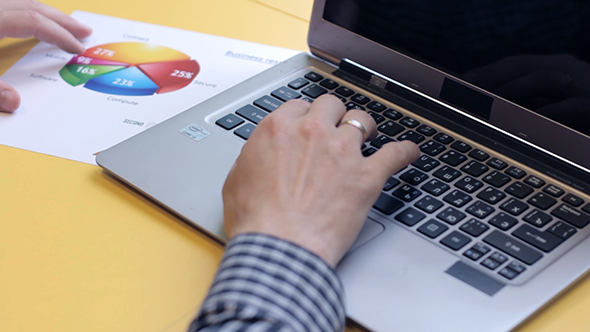 A Man Working On a Laptop And Analyzes The Graph