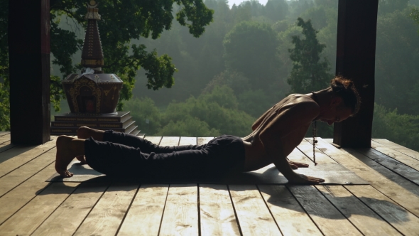 A Man Practices Yoga In The Park With Beautiful Architecture. alt