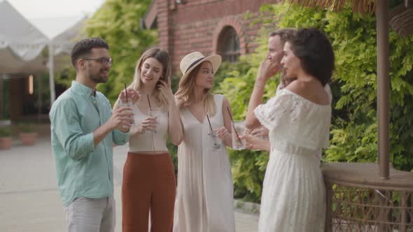 Group of happy young people cheering and having fun outdoors with drinks