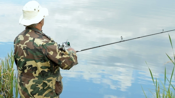 Fisher Man With Fishing Rod Catching Fish On Lake
