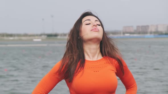 Beautiful athletic woman doing head tilts, stretching her body, warming up before training outdoors. alt