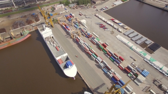 Aerial view of cargo ship in the port with an open hold, awaiting loading