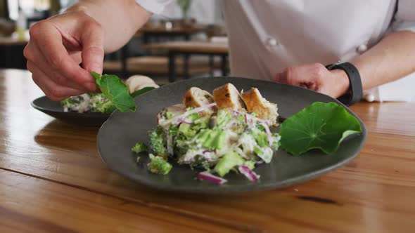 Caucasian female chef preparing a dish and smiling in a kitchen alt
