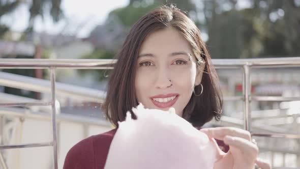 Beautiful young woman eating cotton candy alt