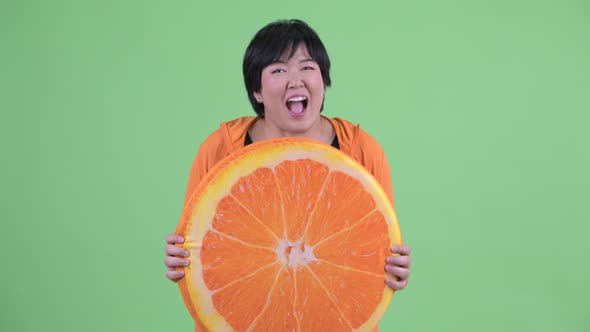 Happy Young Overweight Asian Woman with Orange Pillow As Healthy Concept Ready for Gym alt