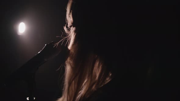 Close-up of the Face of the Singer with Microphone on a Black Smoky Background. The Singer Sings a alt