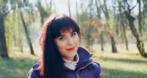 Portrait of Young Attractive Brunet Woman Who Smiling and Looking at the Camera on Autumn Park
