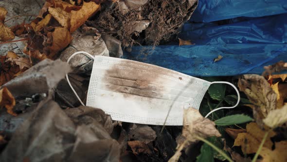 Facial Surgical Mask Used And Thrown Away On The Ground In The Park alt