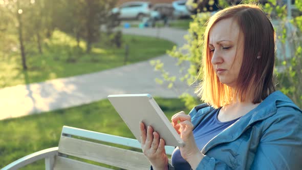 Woman Using Tablet Computer Sitting on Bench in City alt