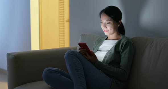 Woman look at mobile phone at home alt