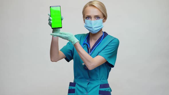 Medical Doctor Nurse Woman Wearing Protective Mask and Gloves - Showing Presenting Mobile Phone alt