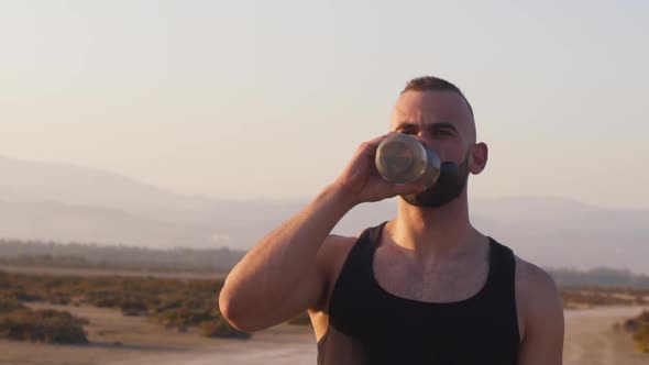 Portrait of Man Working Out in Desert and Drinking Water