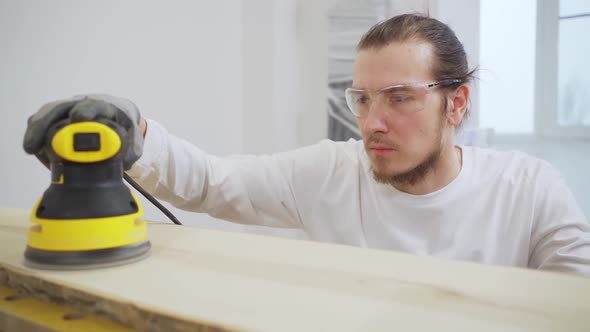 Carpenter in Protective Gloves and Glasses for Working on Wood Grinding Machine alt
