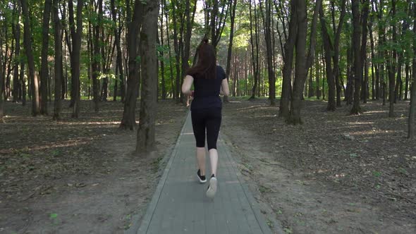 Woman in the Morning Runs in the Forest Along a Narrow Path Made of Tiles