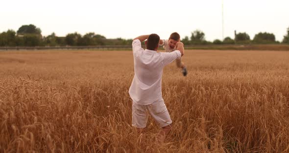 Happy Father Twisting Child on Meadow