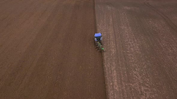 Agricultural Work in the Field, Two Blue Tractors Plow the Land