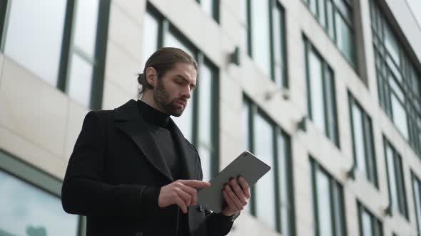 Businessman Using Tablet PC in Front of Offices Building alt