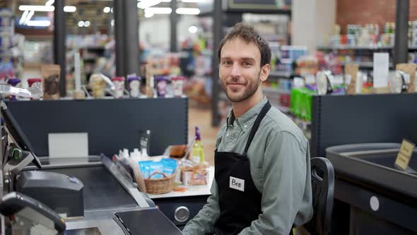 Handsome Man in Supermarket Waiting at Cash Desk for Next Customer alt