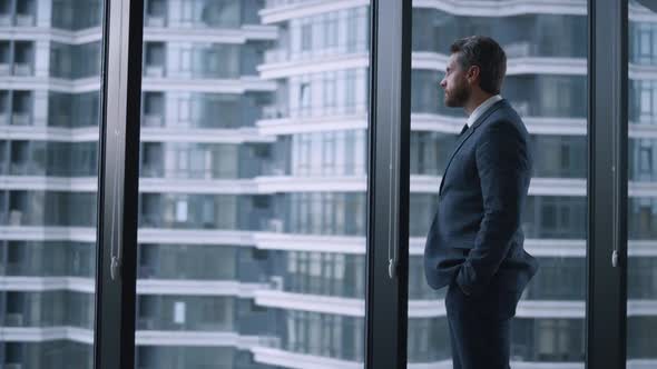 Successful Businessman Crossing Hands Looking Window Wall in Corporate Building alt